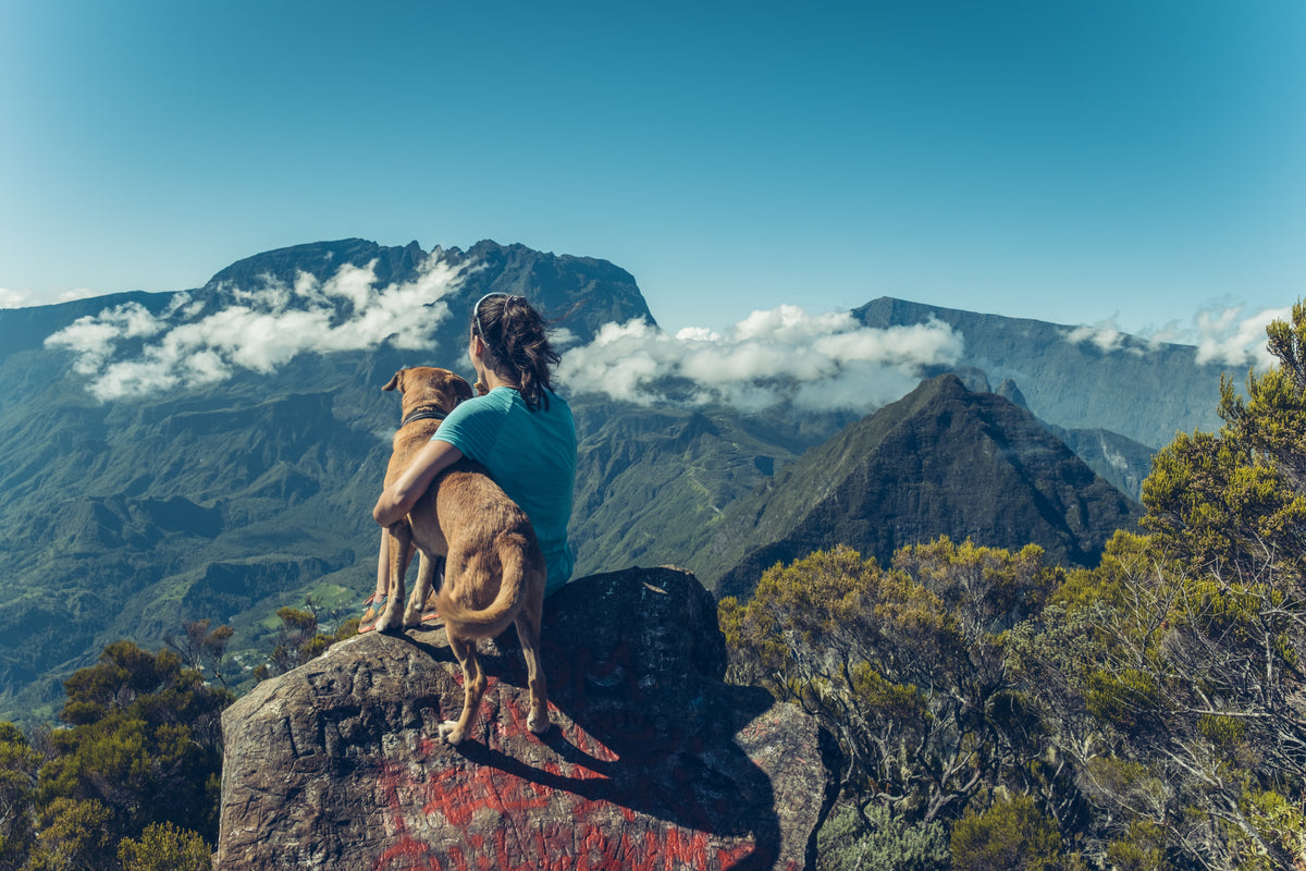 Randonneuse enlaçant son chien face au cirque de Mafate, à La Réunion